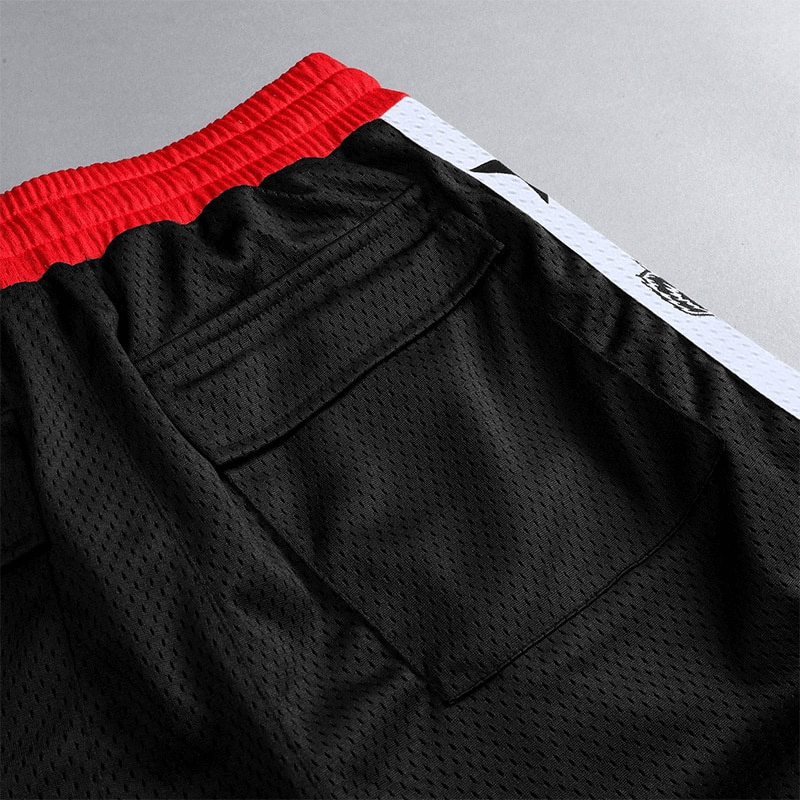 Men's quick-drying black basketball shorts with red waistband, featuring back pocket detail.