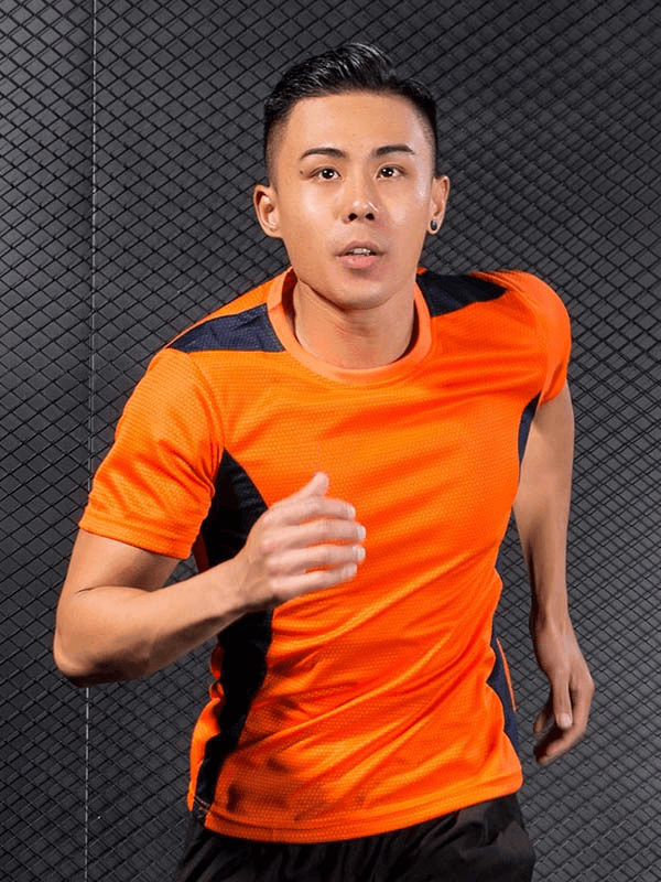 Man wearing vibrant orange quick dry football t-shirt, running energetically against a textured background, perfect for sports and fitness.
