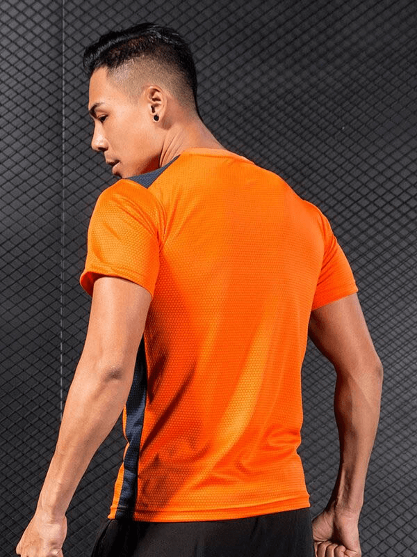 Man wearing orange short sleeves quick dry football t-shirt, ideal for gym or sports, looking at the back, in a modern setting, SF0497.