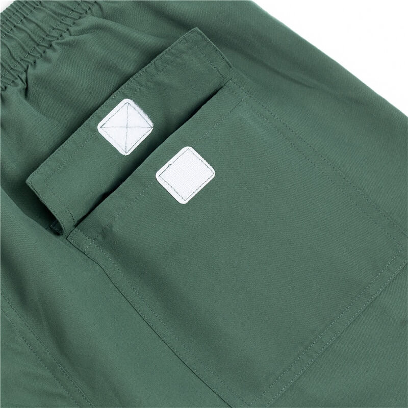 Close-up of green solid color men's boardshorts with pockets, featuring durable polyester fabric and stylish design for swimming.
