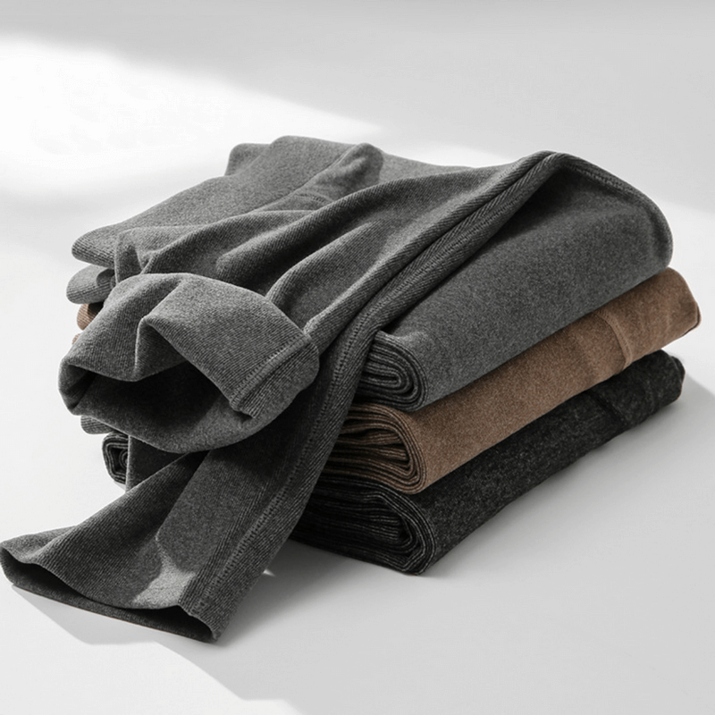 Stack of folded men's solid color thermal pants in various shades, showcasing heavyweight fabric and elastic waistband for comfort.