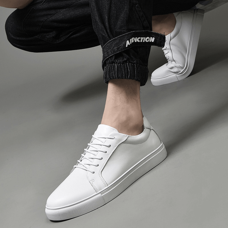 Men's white sports flexible leather sneakers with flat sole, featuring a comfortable lace-up design and rubber outsole for a sleek, modern look.