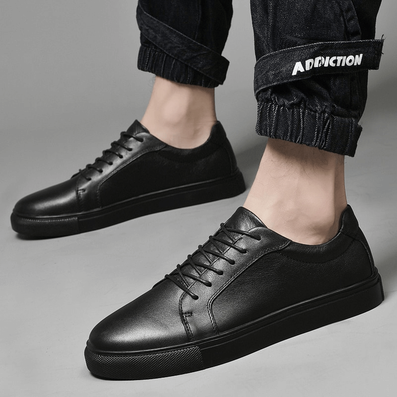 Men's sports flexible leather sneakers with flat sole and lace-up closure in black, showcasing comfort and modern style.