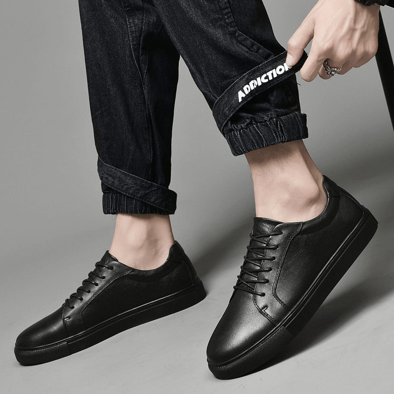 Men's black leather sports sneakers with flat soles, featuring a breathable design and massage insole. Perfect for modern casual wear.