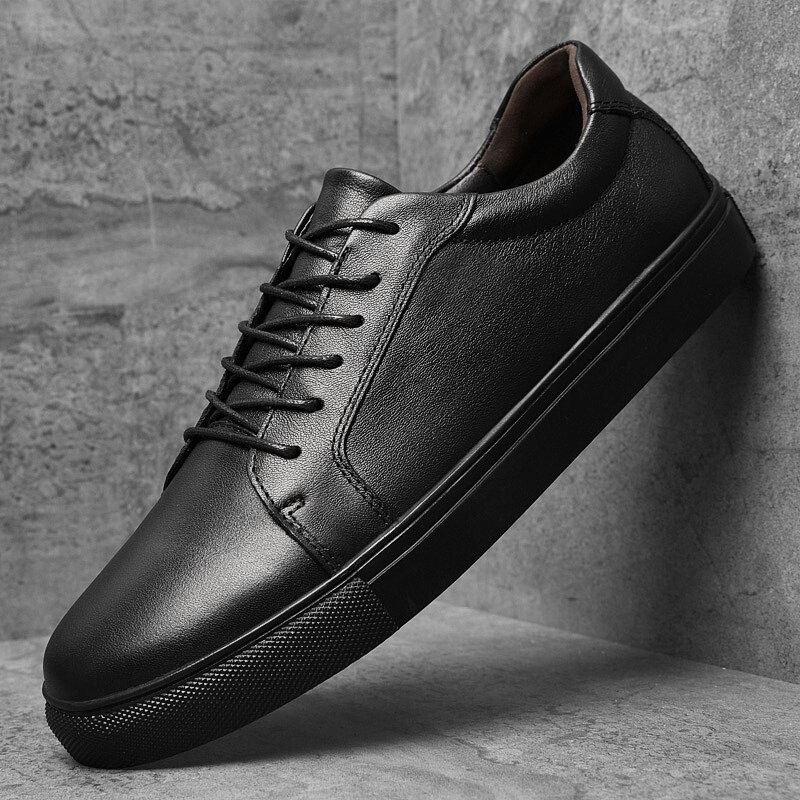 Men's leather sports sneakers with flexible flat sole and lace-up closure, in black, featuring a breathable design and massage insole.