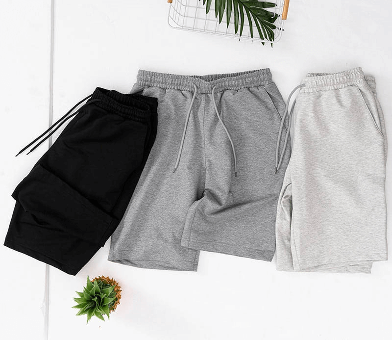 Men's sports loose cotton shorts in black, grey, and light grey colors on a white background, ideal for running and comfort.