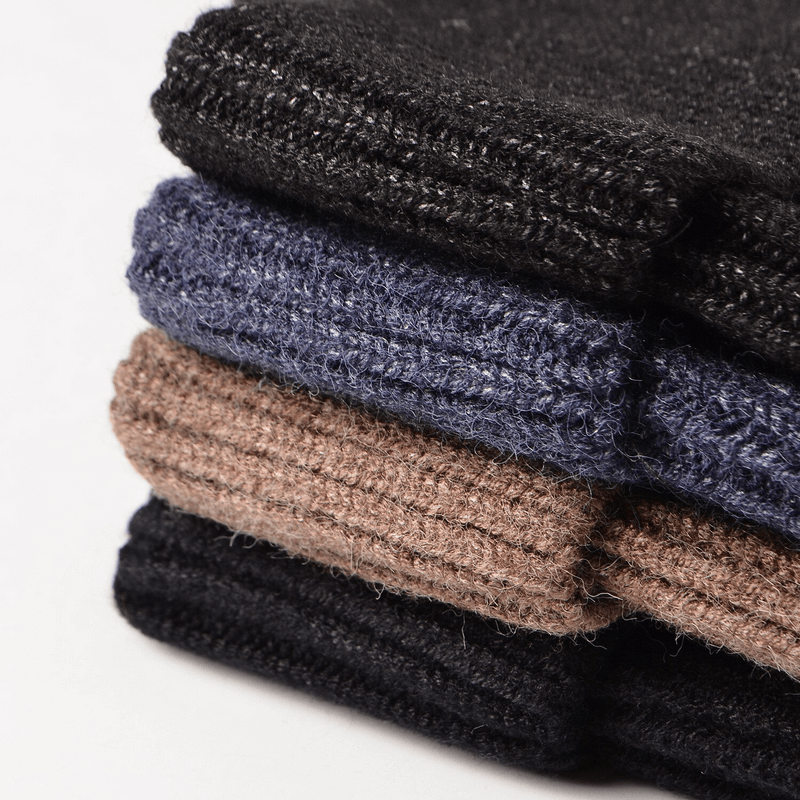 Stack of men's knitted hats in black, navy, camel, and charcoal, showcasing warm textured designs for running and outdoor activities.