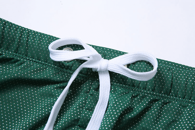 Close-up of Men's Swimming Drawstring Boxers with classic dot pattern and white bow on green fabric for beachwear.