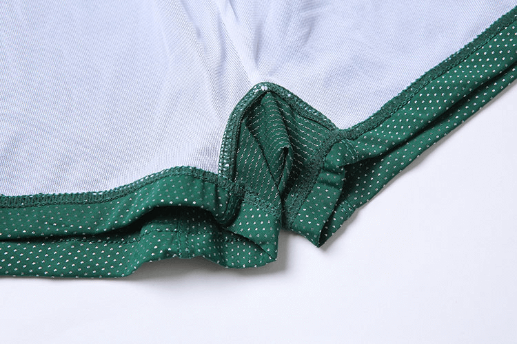Close-up of green men's swimming boxers with dotted pattern and adjustable drawstring, showing durable polyester material.