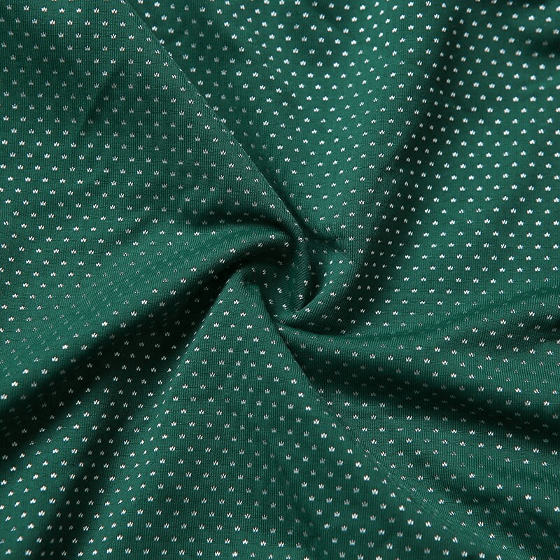Close-up of green fabric with small white dots, showing texture and design.