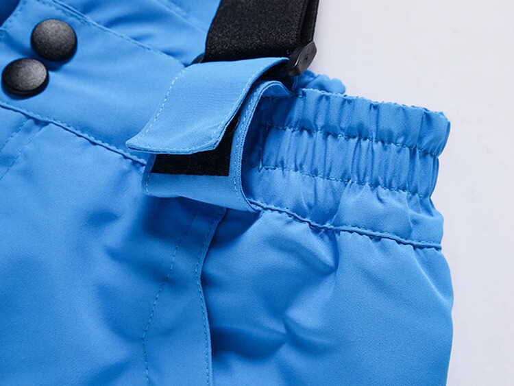 Close-up of blue men's ski pants waistband showing button detail and elastic for a comfortable fit. Windproof, breathable fabric.