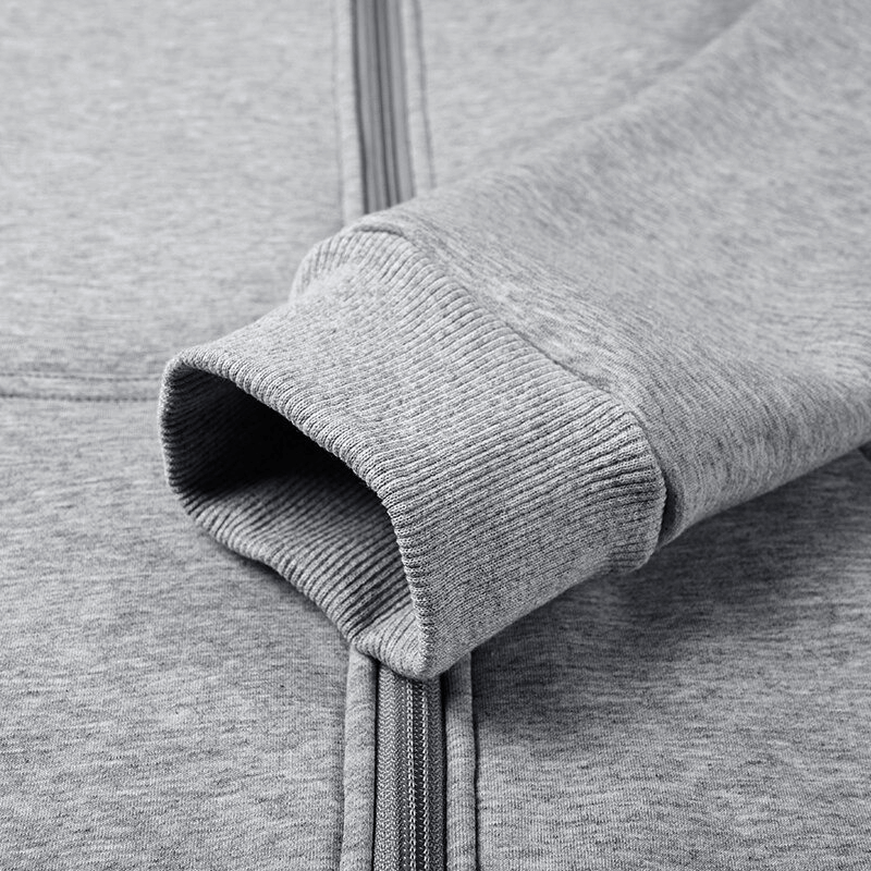 Close-up of a grey men's zip-up thick warm hoodie sleeve with ribbed cuff, showcasing detailed stitching and quality fabric texture.
