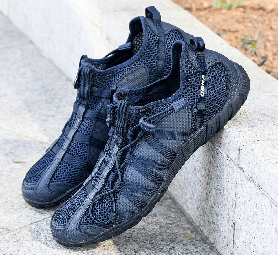 Mesh breathable lightweight men's sneakers with flexible soles on pavement, showcasing durable air mesh upper and rubber outsole.