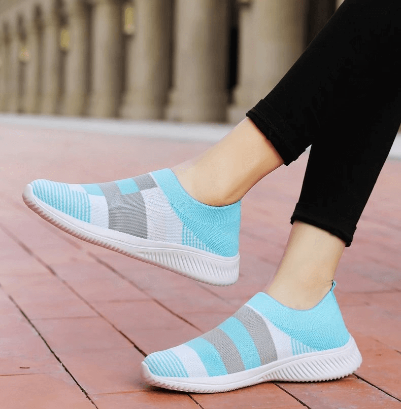Woman wearing blue and gray mesh breathable women's shoes, stylish sports sneakers, on a brick pathway.