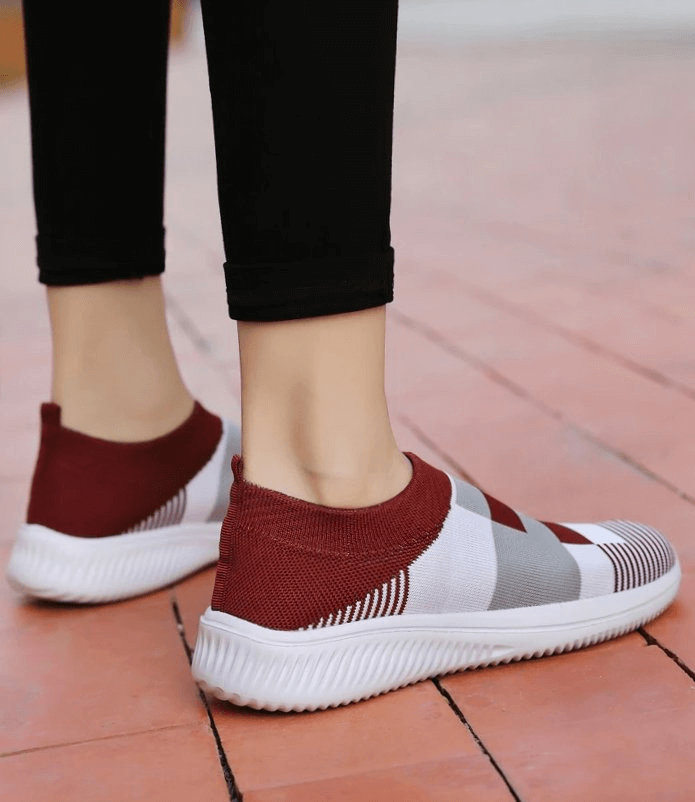 Woman wearing mesh breathable stylish red and white sports sneakers, perfect for casual or active wear.