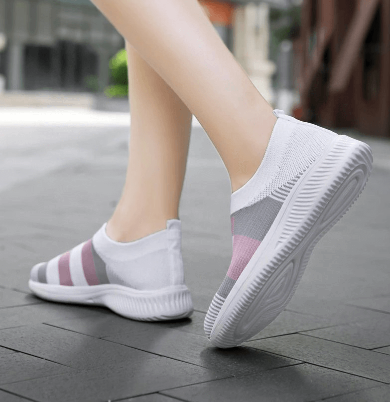 Woman wearing mesh breathable women's shoes, stylish sports sneakers in urban setting, showcasing comfort and slip-on design.