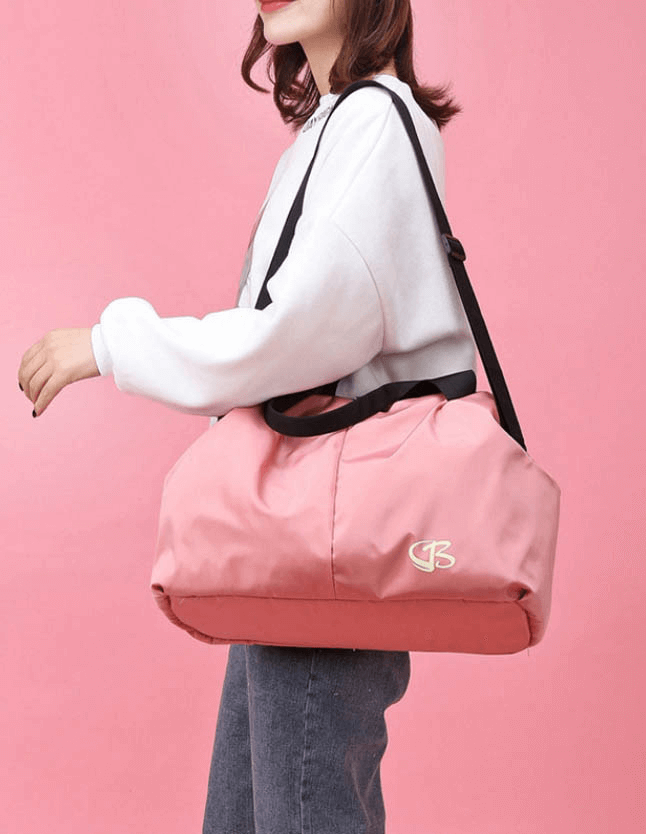 Woman carrying pink multifunction waterproof gym bag for sports and travel, stylish and durable with large capacity.