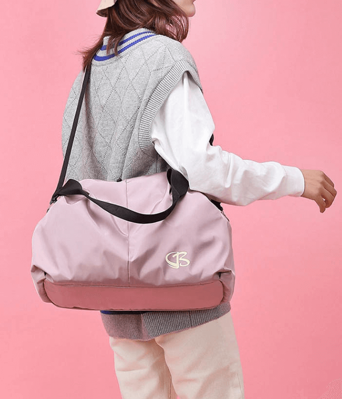 Stylish woman carrying pink multifunction waterproof gym bag with black straps against a pink backdrop, ideal for active lifestyles.