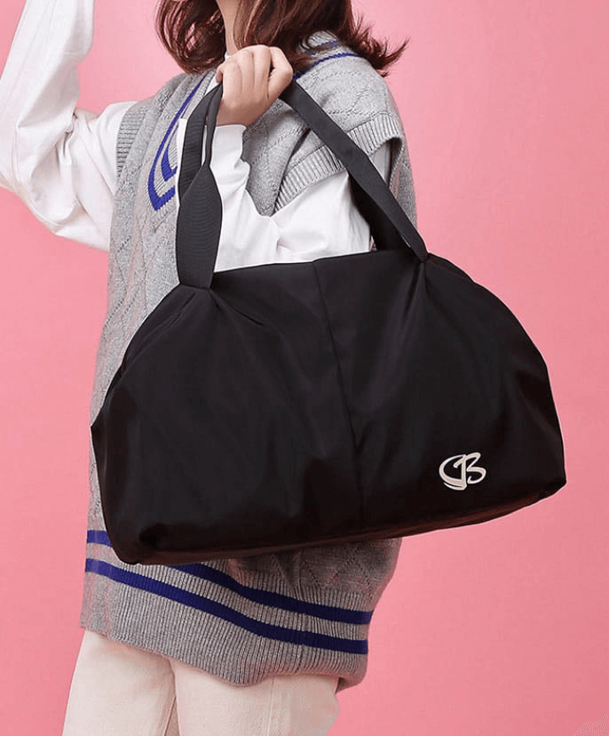 Multifunction waterproof women's gym bag in black held by a woman, showcasing large capacity and stylish design for fitness and travel.