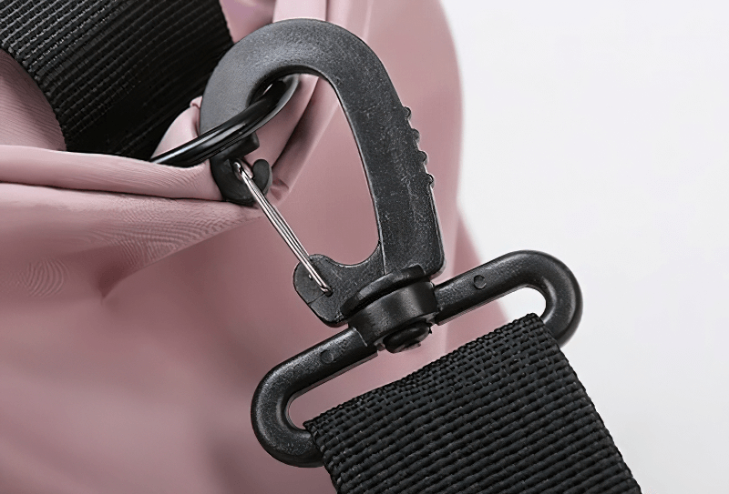 Close-up of pink multifunction gym bag's durable strap attachment showing a sturdy black clip.