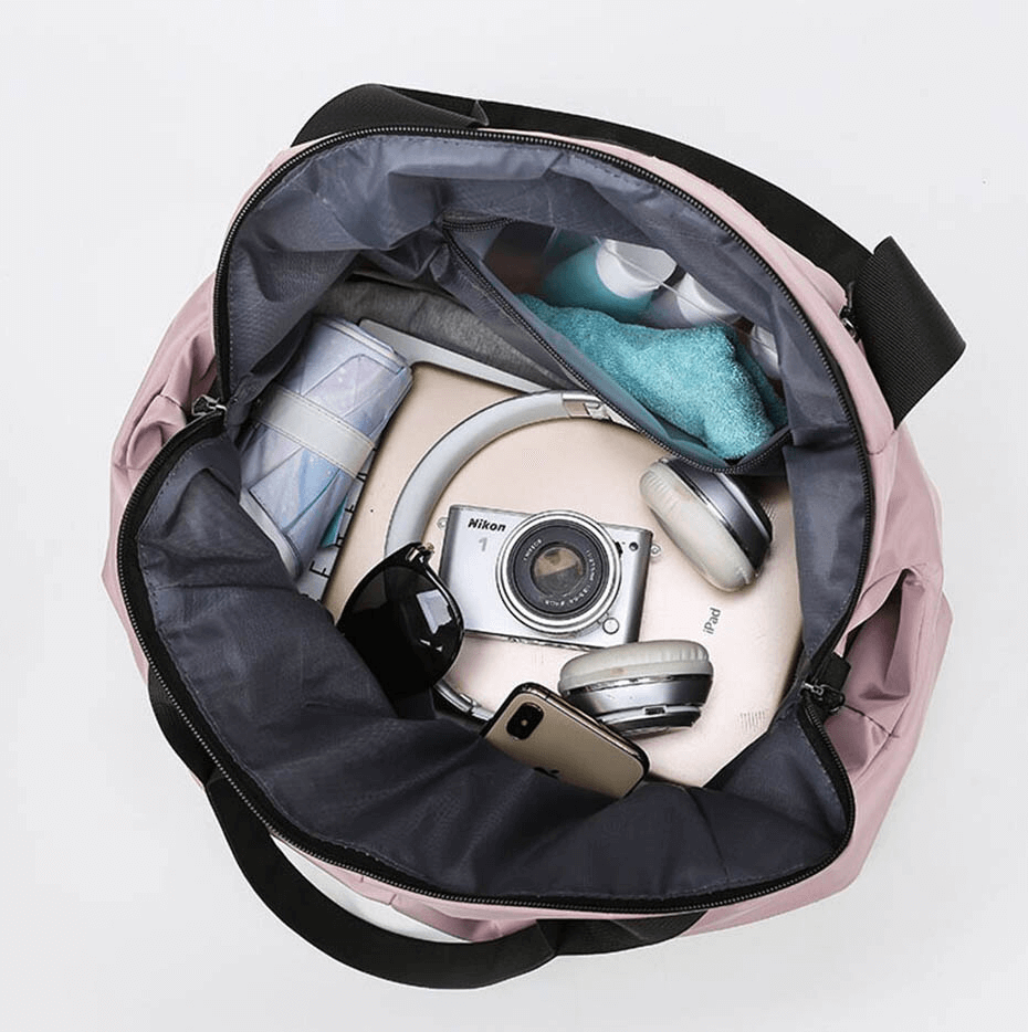 Open pink waterproof gym bag with camera, headphones, towel, and other essentials, showcasing large capacity and multifunctionality.