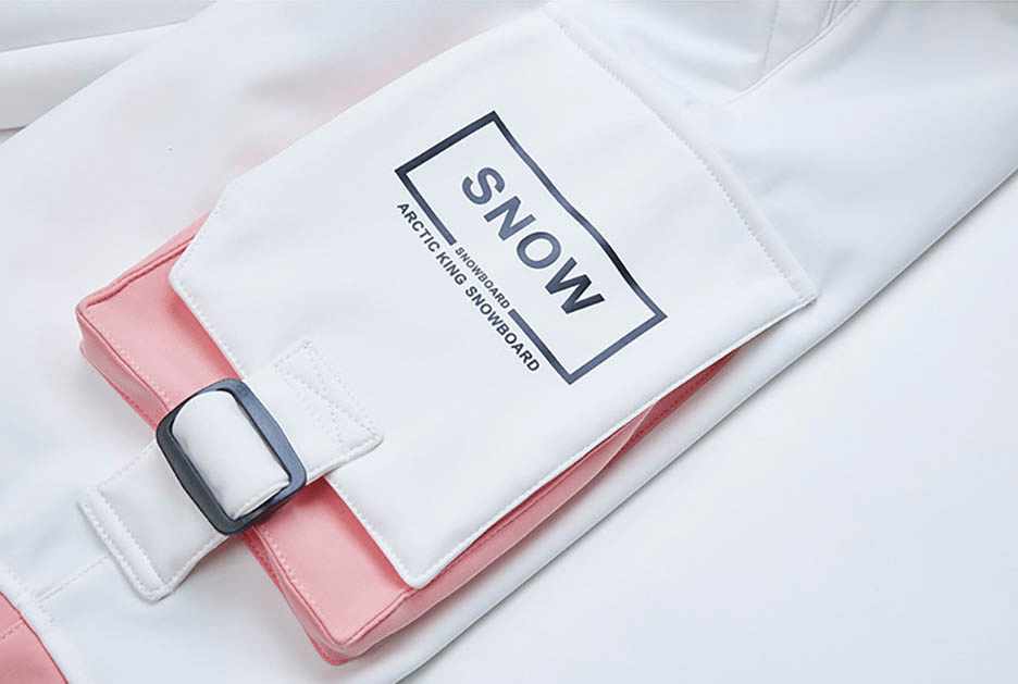 Close-up of pink and white ski pants with belt and pocket labeled 'SNOW' for outdoor winter activities.