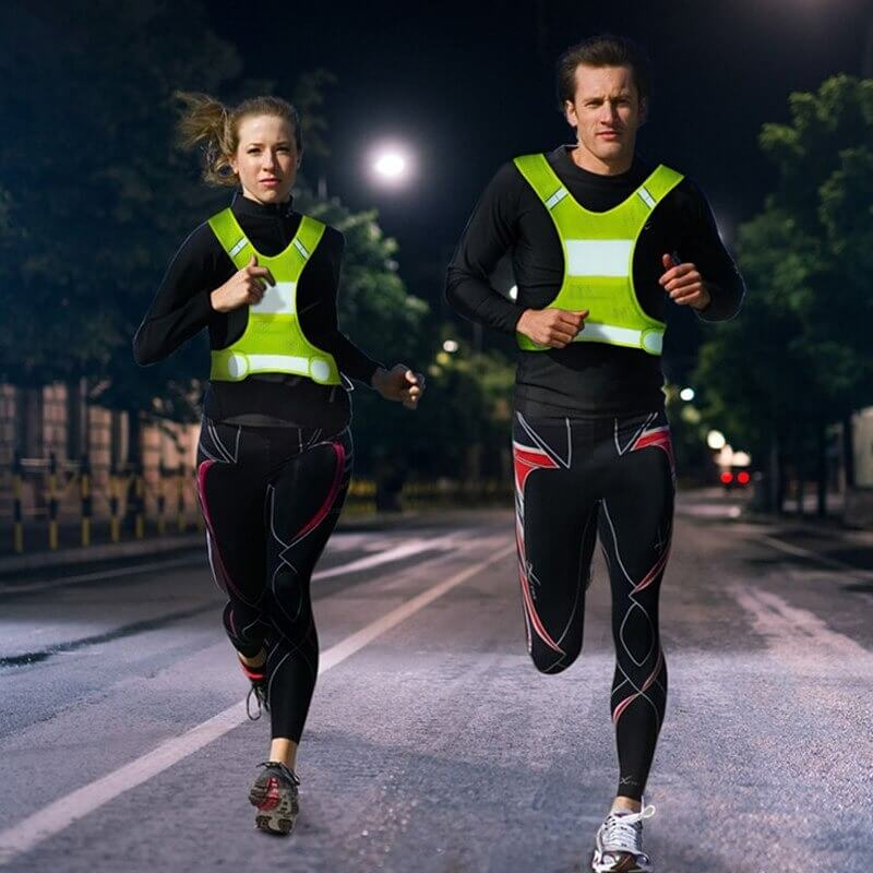 Runners wearing outdoor reflective security vests jogging at night for enhanced visibility and safety.