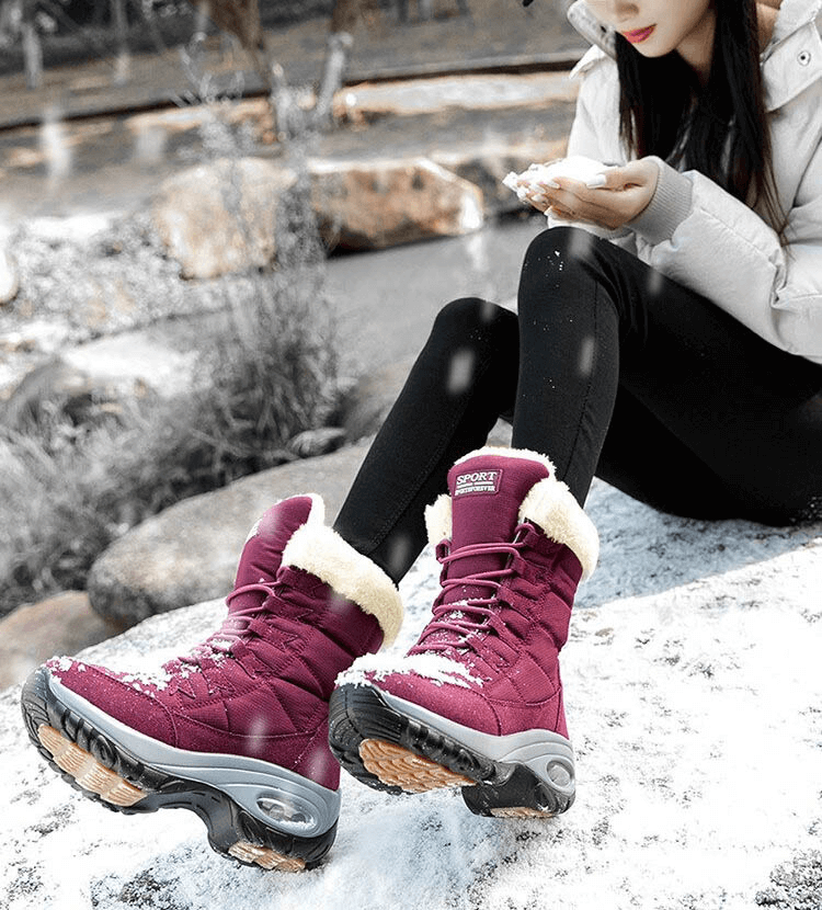 Woman wearing warm waterproof snow boots seated on a snowy rock with winter scenery, showcasing SF0288 trekking shoes for women.