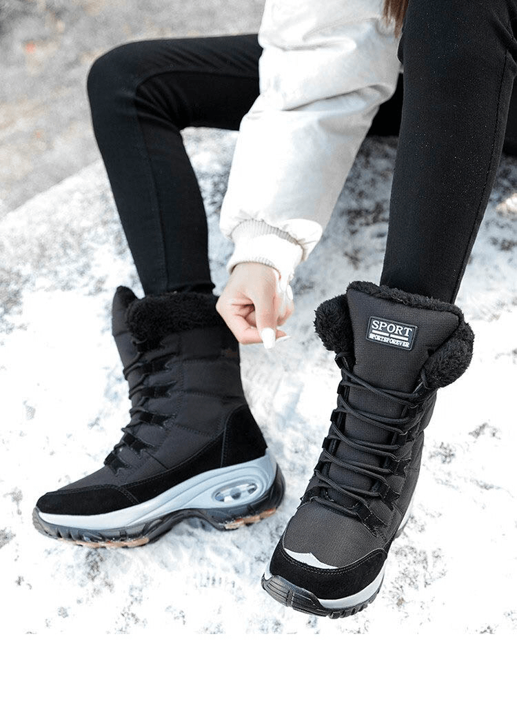 Woman wearing black waterproof snow boots for trekking on icy terrain, featuring warm lining and durable rubber soles.