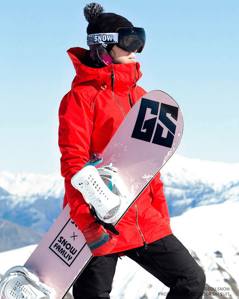 Woman in red waterproof snowboarding jacket holding a snowboard on a snowy mountain