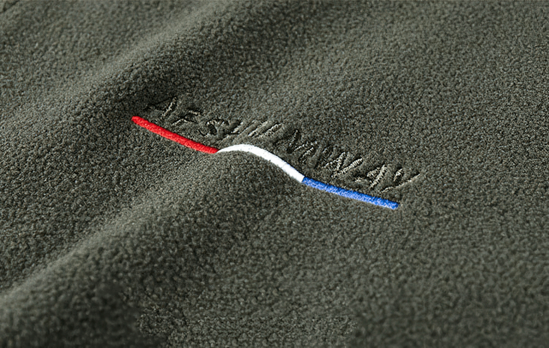 Close-up of the Outdoor Zipper Fleece Hiking Jacket in green fabric with embroidered logo and red, white, blue detailing.