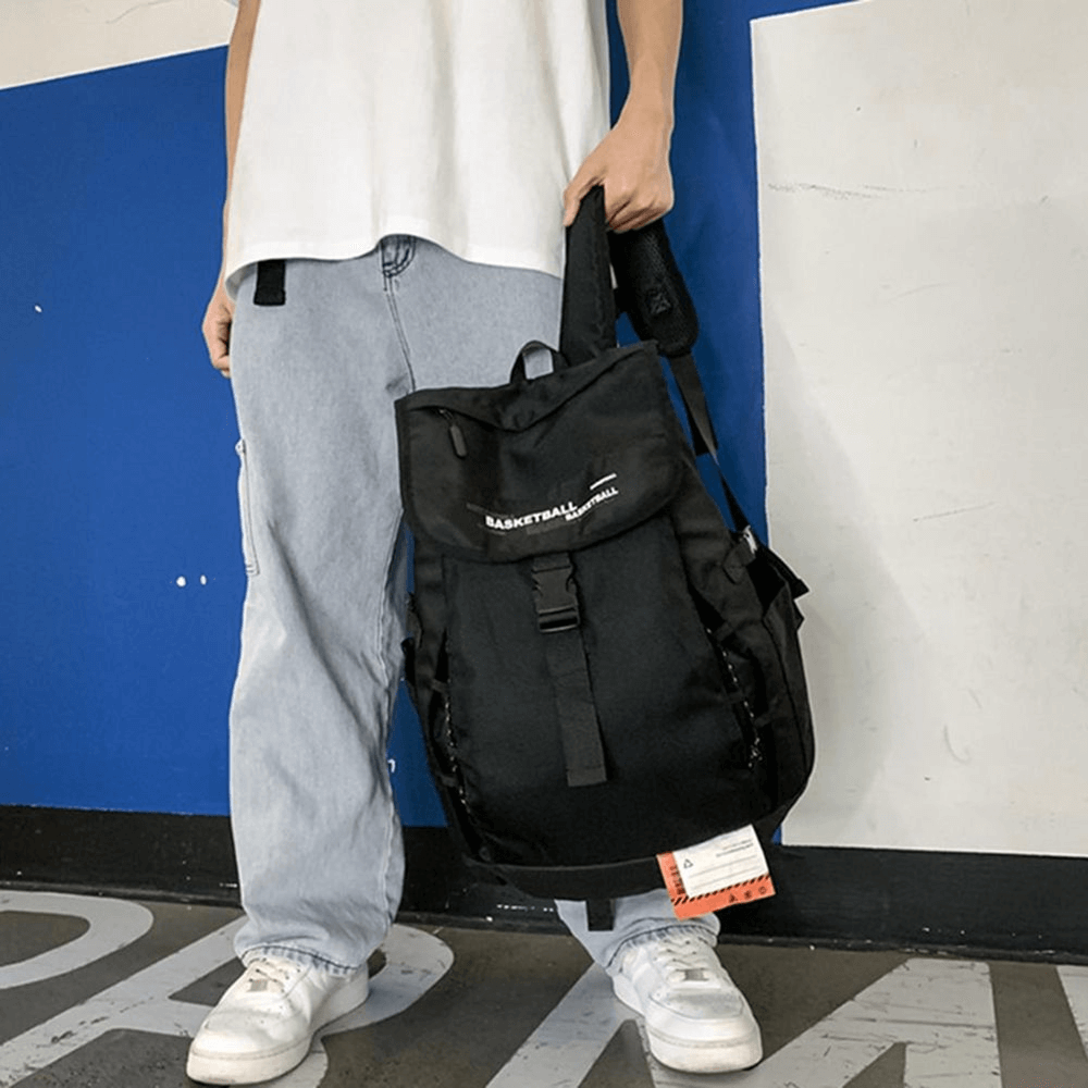 Unisex black basketball backpack with ball pocket and adjustable straps for outdoor sports, shown against a modern urban background.