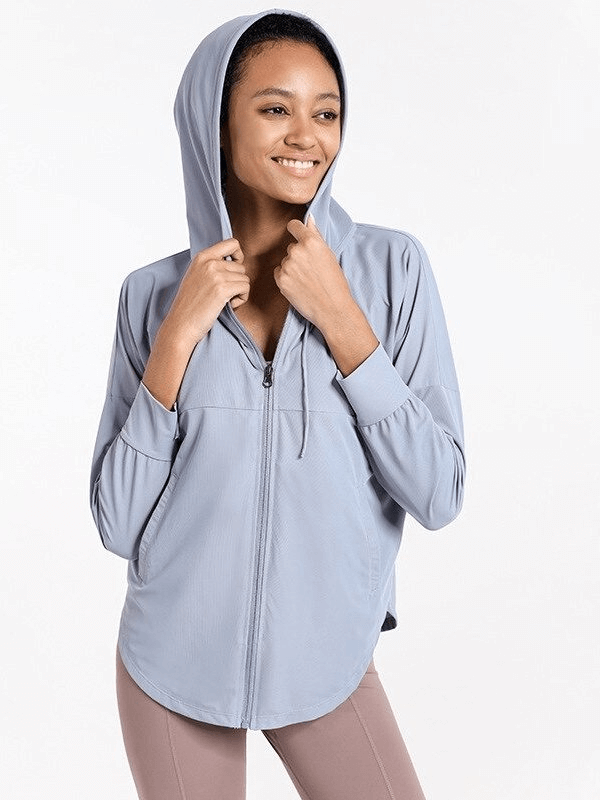 Woman wearing light blue sports loose jacket with hood, ideal for jogging and yoga. Made of breathable, quick-dry fabric. Model SF0138.