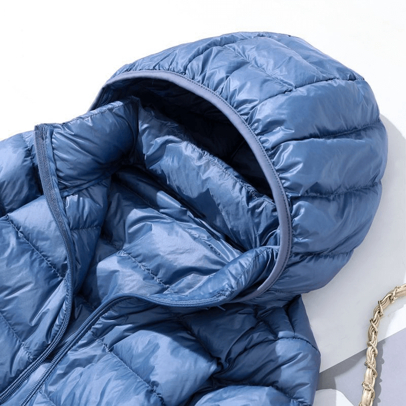 Close-up of blue windproof puffer jacket with detachable hood and double zipper, crafted from lightweight nylon and duck down.