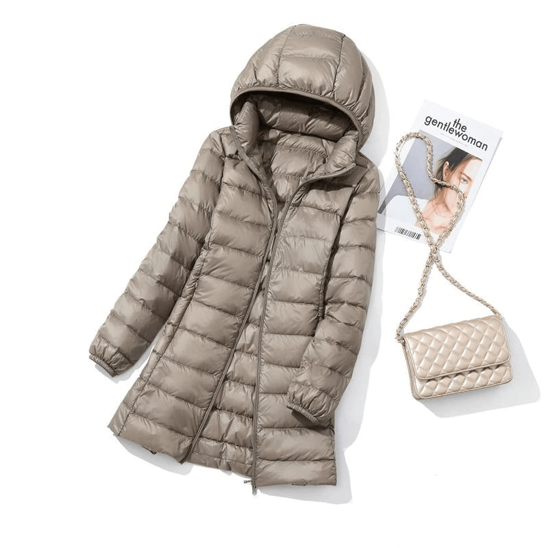 Stylish puffer jacket with detachable hood, double zipper, and quilted pattern beside a quilted bag and magazine.