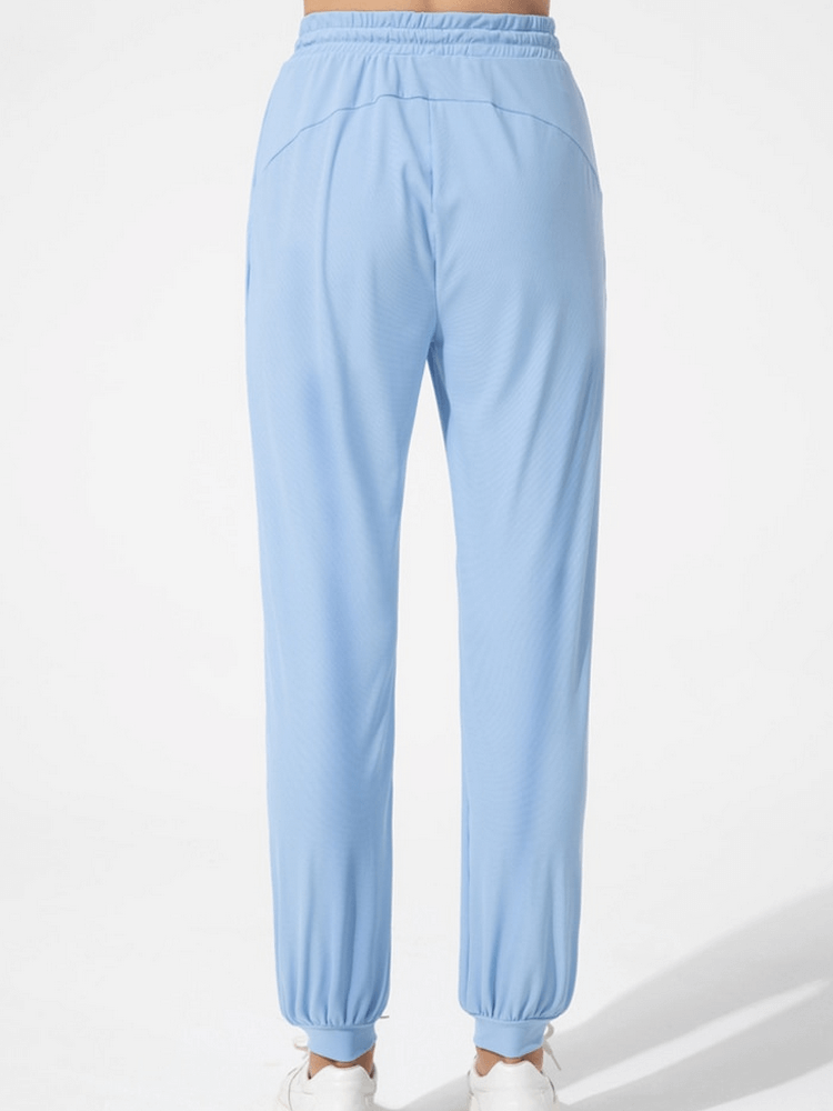 Back view of quick-drying lightweight women's training pants in blue with pockets and drawstring, perfect for yoga and sports.