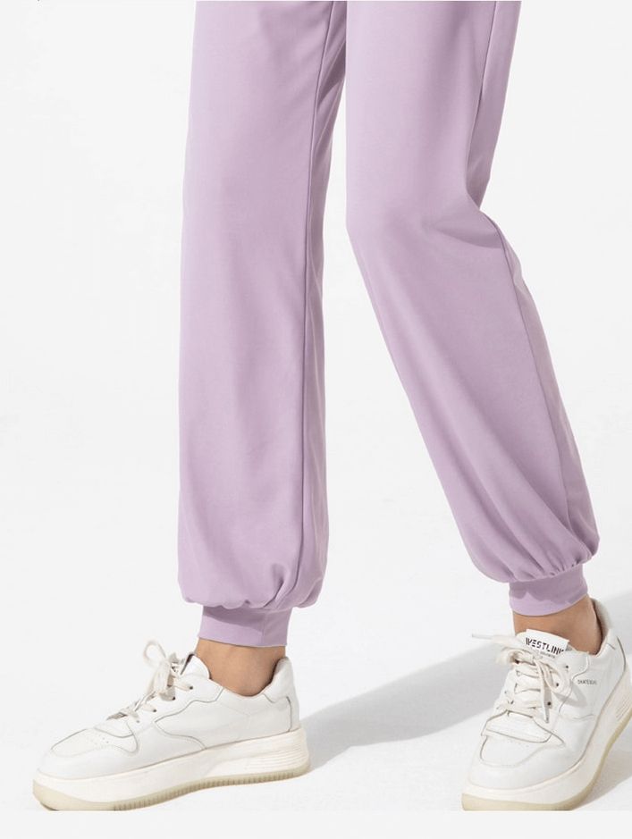 Woman wearing quick-drying sports lightweight training pants with pockets and white sneakers, showcasing ankle-length fit.