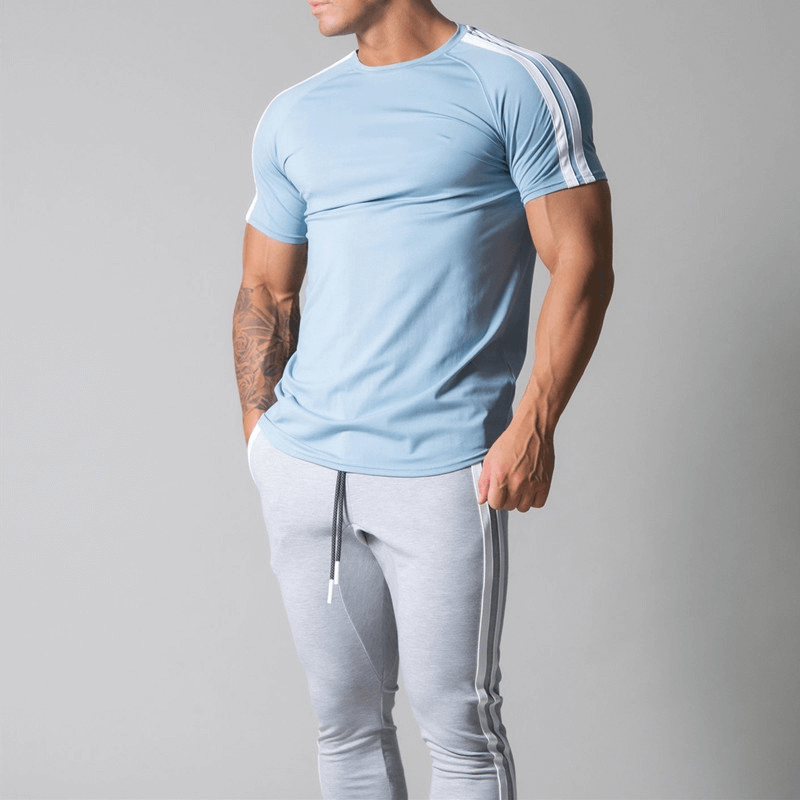 Man wearing a stylish blue cotton running t-shirt with striped sleeves, paired with gray joggers. Perfect for athletic comfort and style.