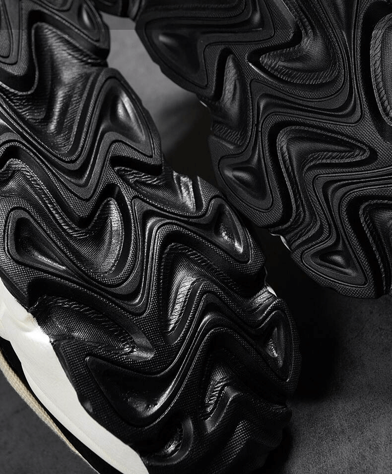 Close-up of running sneakers' black ripple-textured thick soles, showcasing durable EVA outsole for shock absorption.