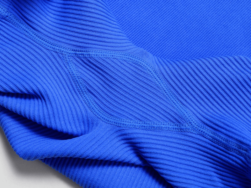 Close-up of blue seamless one piece short yoga suit fabric, showcasing its ribbed texture and breathable design for active women.