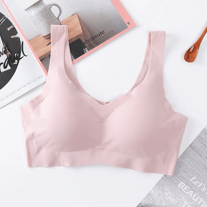 Seamless solid color women's sports bra for fitness in pink, wire-free with padded cups and adjustable straps on a stylish background.