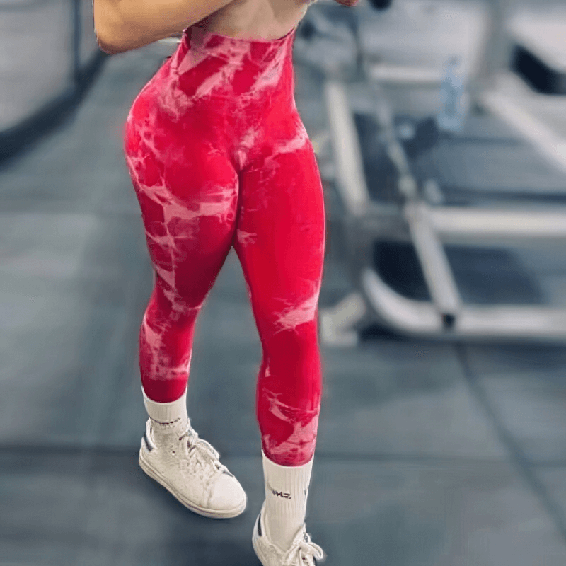 Woman wearing red seamless tight leggings with push-up effect, showcasing high waist and ankle-length style in a gym setting.