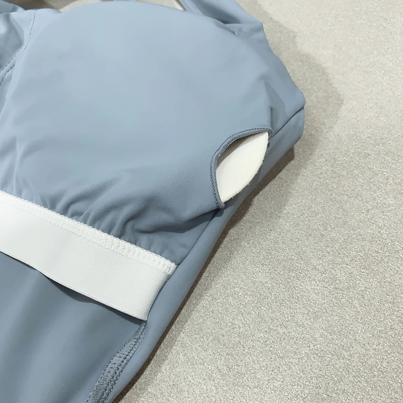 Light blue cross back running tank top with white band, featuring breathable nylon and spandex for high-intensity workouts.