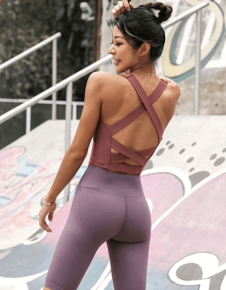 Woman wearing a stylish sexy cross back running tank top for workouts, perfect for yoga and high-intensity activities.