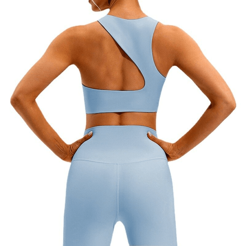 Back view of a woman wearing a blue open-back elastic sports bra and leggings, showcasing stylish fitness wear ideal for workouts.