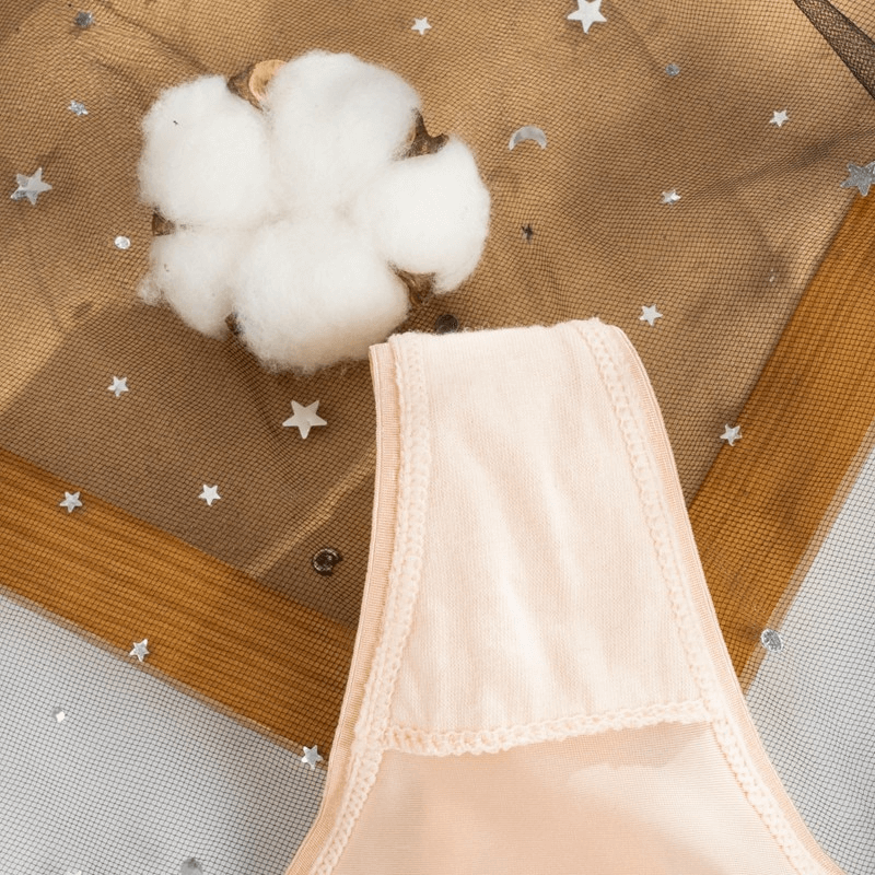 Close-up of a sexy lace breathable women's thong with a peach color, featuring a delicate design and cotton plant beside it.