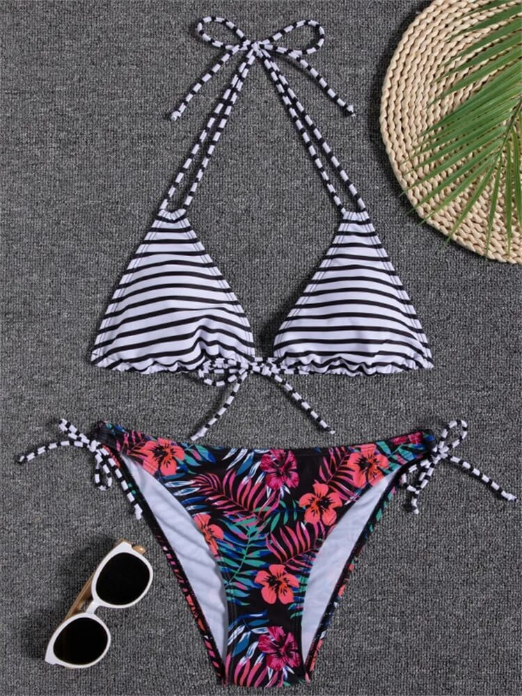 Striped and floral print two-piece bikini with sunglasses on gray background.