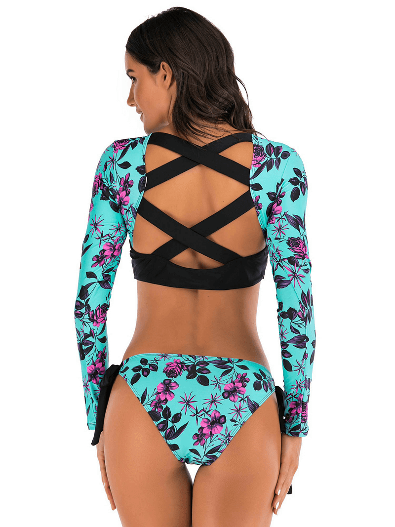 Woman modeling a floral long-sleeve backless two-piece swimsuit in blue and purple. Stylish swimwear perfect for summer.