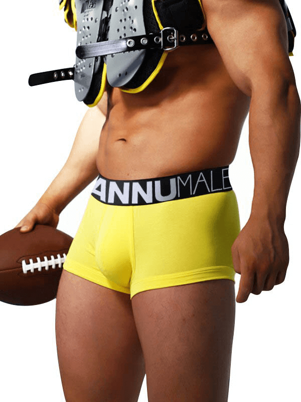 Man holding football in yellow breathable sports cotton boxers with letter pattern waistband, emphasizing comfort and performance.