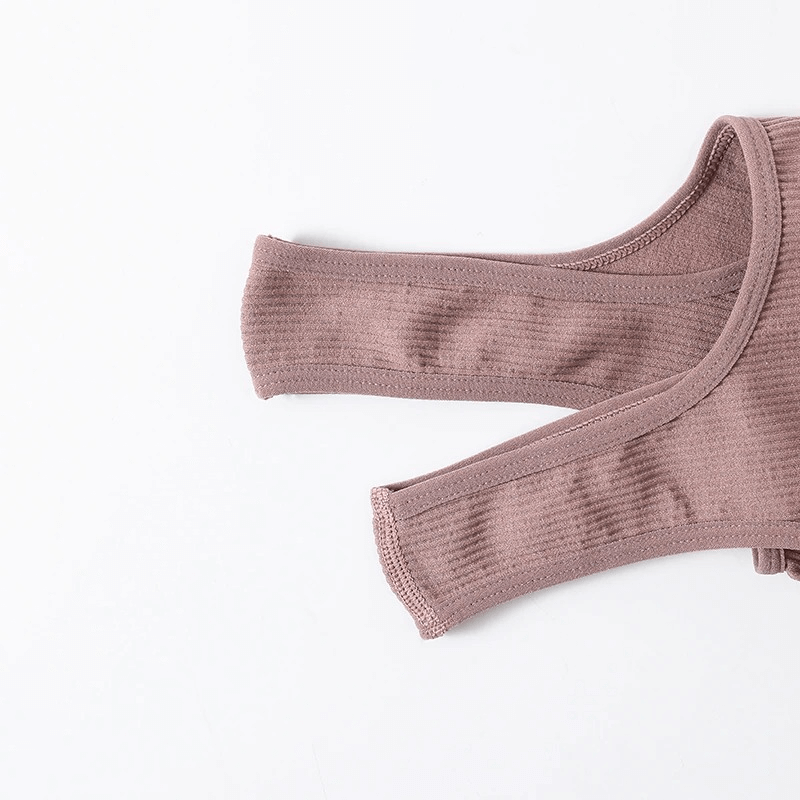 Close-up of mauve ribbed seamless women's tank top straps on a white background, highlighting the material texture.